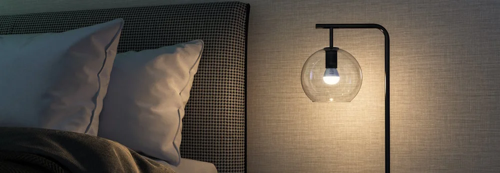 Beleuchtete Nachttischlampe neben Bett